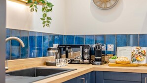 Una cuina moderna amb cafetera, bullidor i un rellotge a la paret.