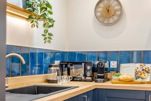 Eine moderne Küche mit Kaffeemaschine, Wasserkocher und einer Wanduhr.