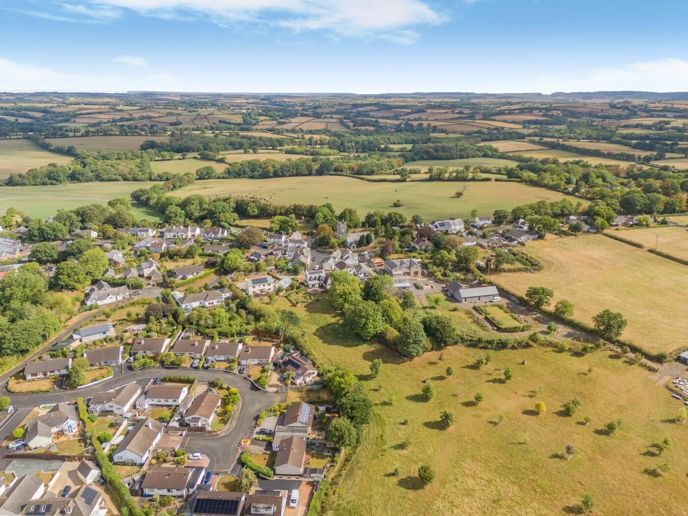 Ein Wohngebiet mit Häusern, Straßen und grünen Feldern.