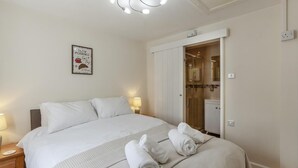 Quarto de hotel com cama, abajures, chuveiro e um quadro na parede.