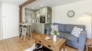 Um espaço compacto com cozinha compacta, área de refeições e sala de estar com sofá e mesa de centro.