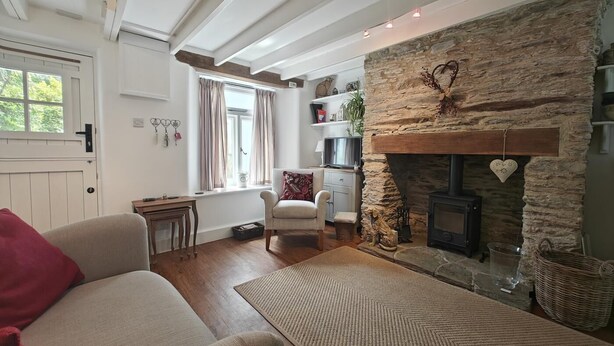 Una sala acogedora con chimenea de piedra, un sofá, un sillón y una televisión.