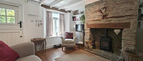 A cozy living room with a stone fireplace, a sofa, a chair, and a television.