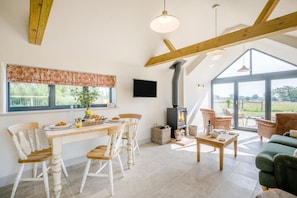 Ein gemütliches Zimmer mit Essbereich, einer Couch, einem Kamin und einem großen Fenster.