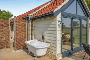 Ein Badezimmer mit einer freistehenden Badewanne, einer Duschkabine und einem Fenster mit Blick auf einen Garten.