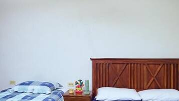 A bedroom with two beds, a wooden headboard, a nightstand, and a ceiling fan.