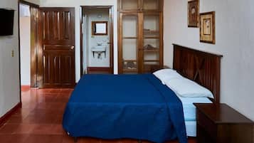 A bedroom with a bed, a wardrobe, a mirror, and a television.