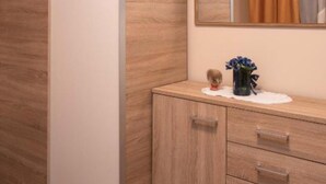 A wooden cabinet with drawers, a mirror above it, and a vase with flowers on a white cloth.