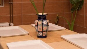 A table with a decorative vase, a plant, and two empty white plates.