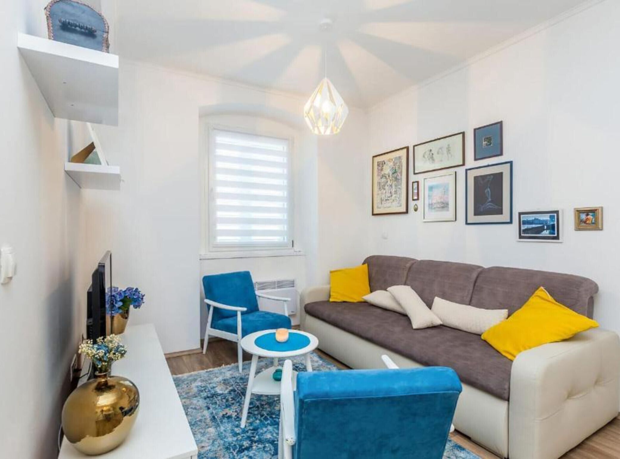 Un salon moderne avec un canapé, un fauteuil bleu, une petite table et un vase décoratif.