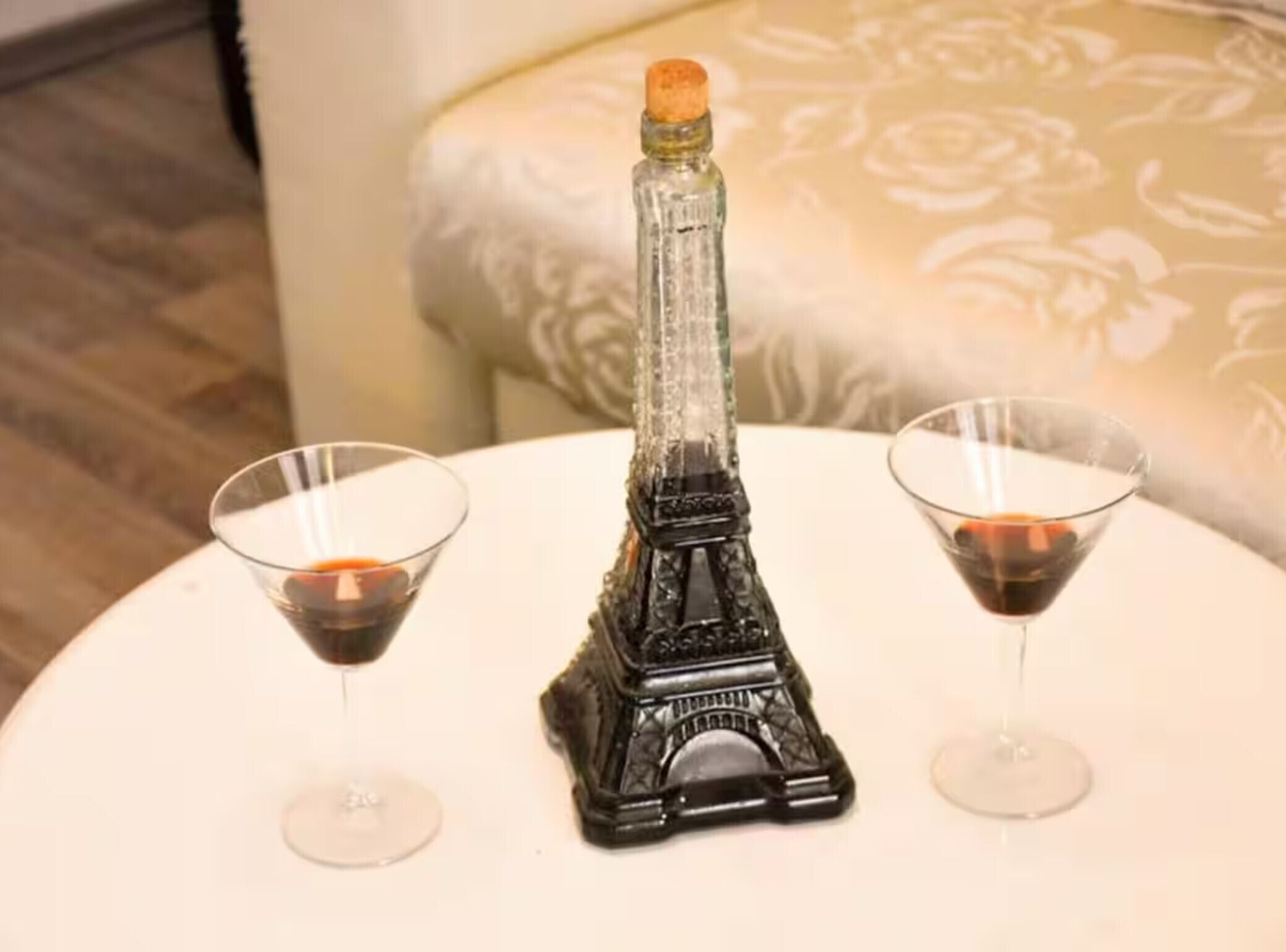 Une table ornée d’une bouteille décorative en forme de tour Eiffel et de deux verres à martini.