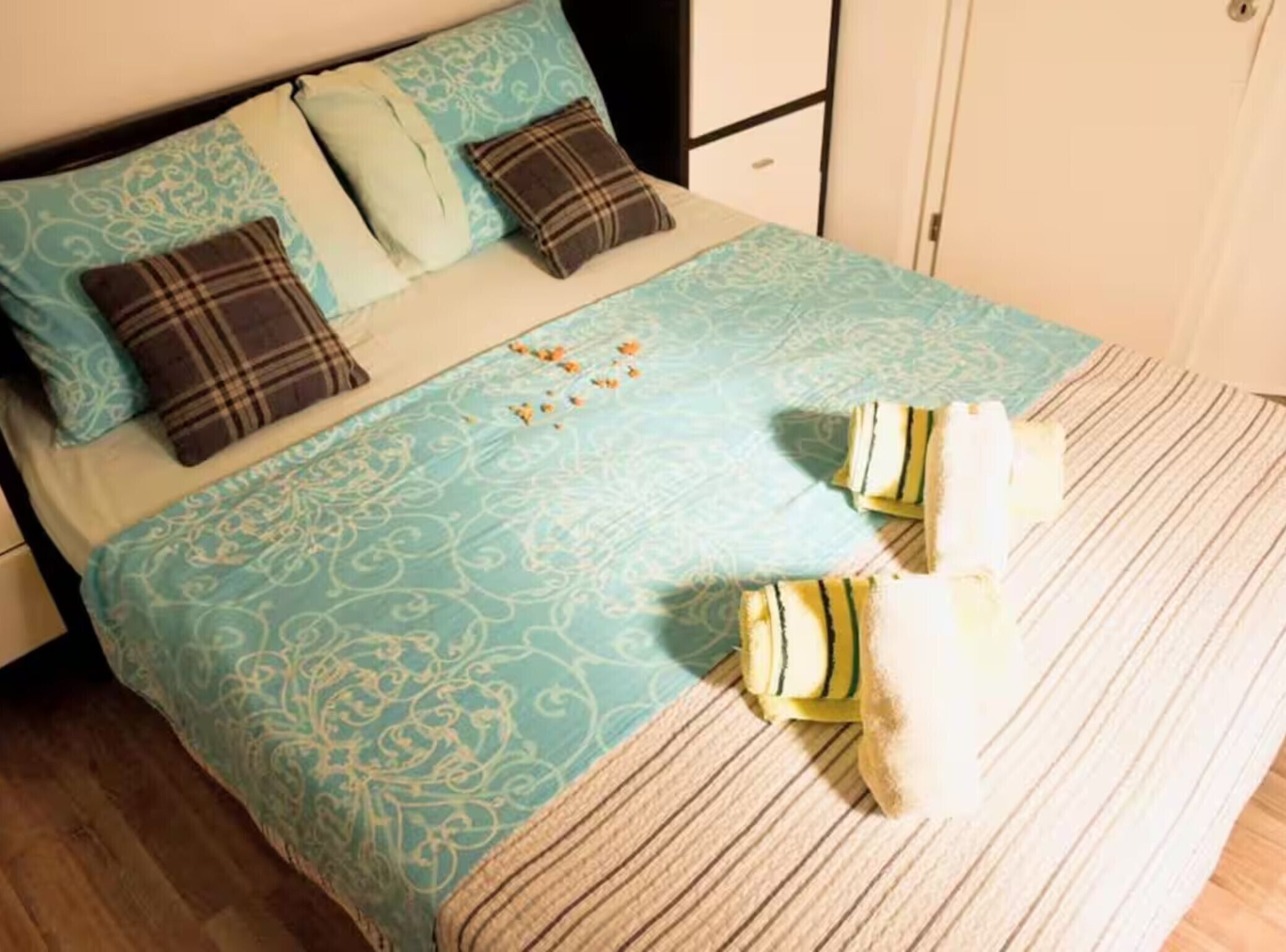 Una cama con una colcha estampada, dos almohadas y un pequeño adorno sobre la misma.