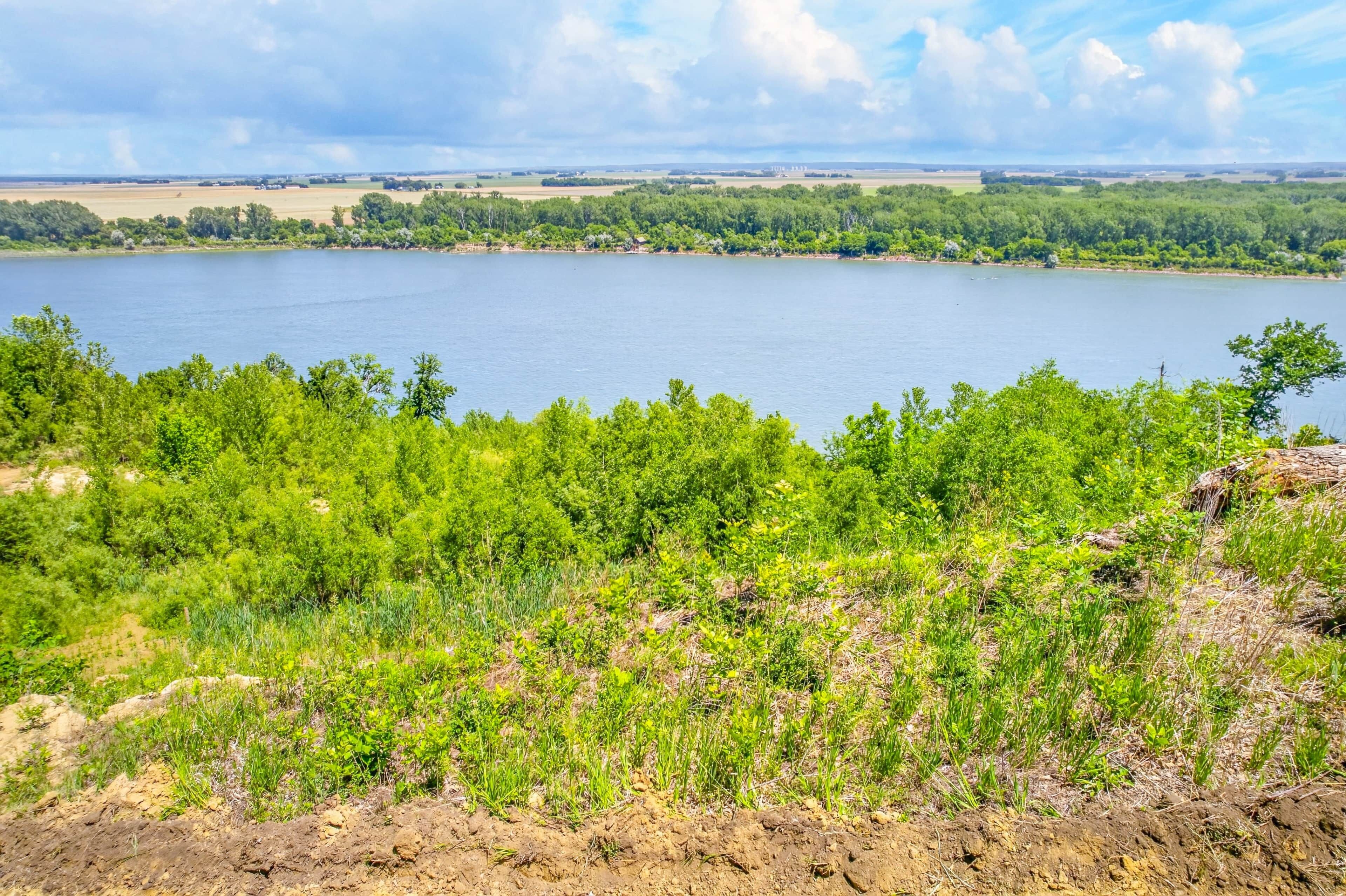 A lake with a forested shoreline and distant buildings.