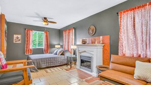 Ein Zimmer mit einem Bett, einem Sofa, einem Kamin und einem Deckenventilator.