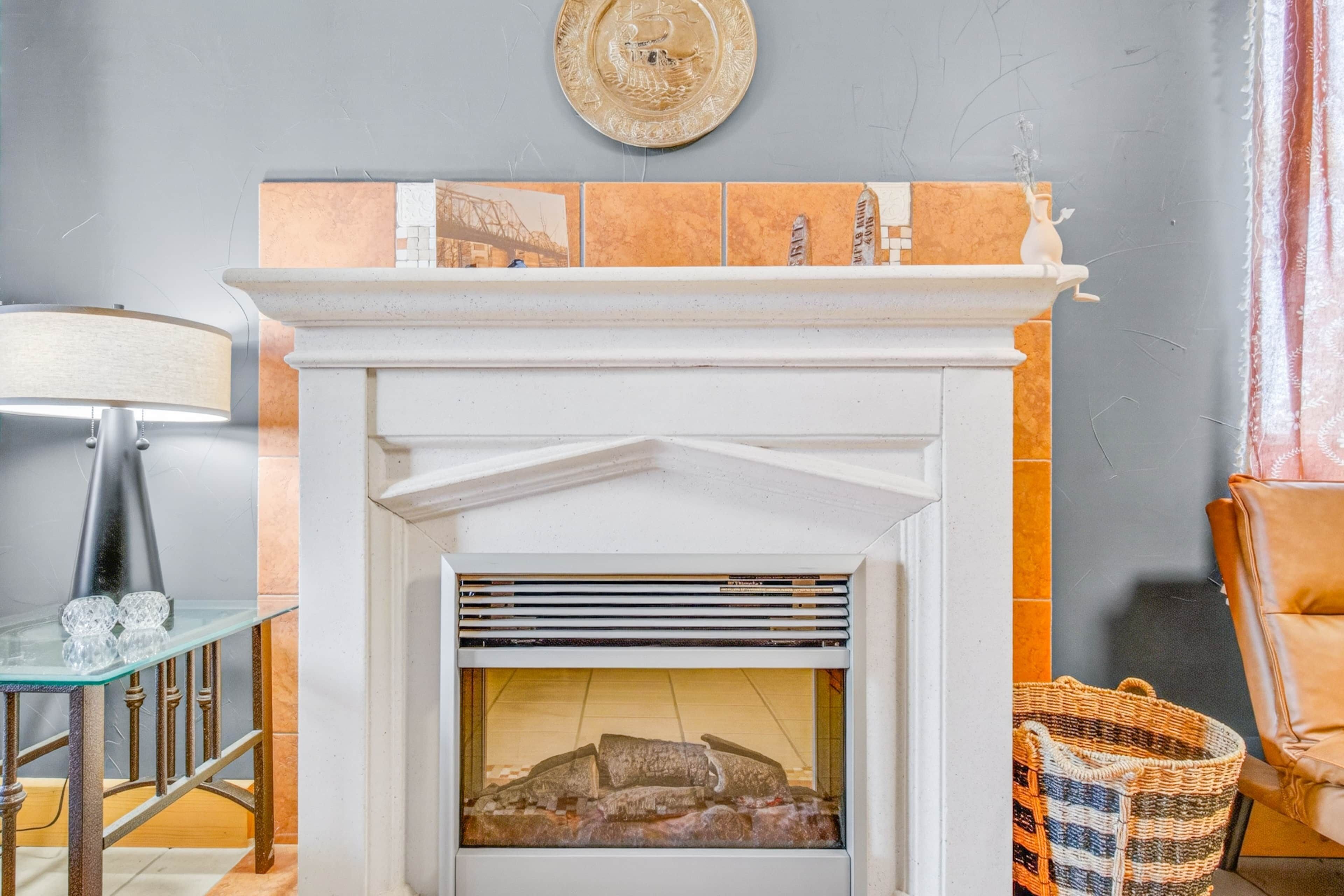 A fireplace with a tiled mantle, a glass table with crystal, and a wicker basket.