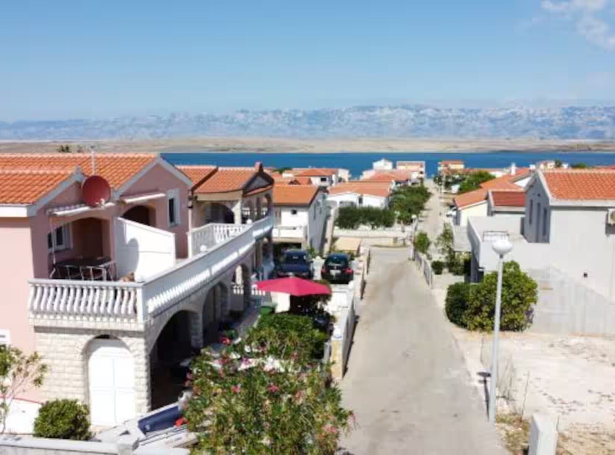 A coastal street with buildings, a clear sky, and a view of the sea.