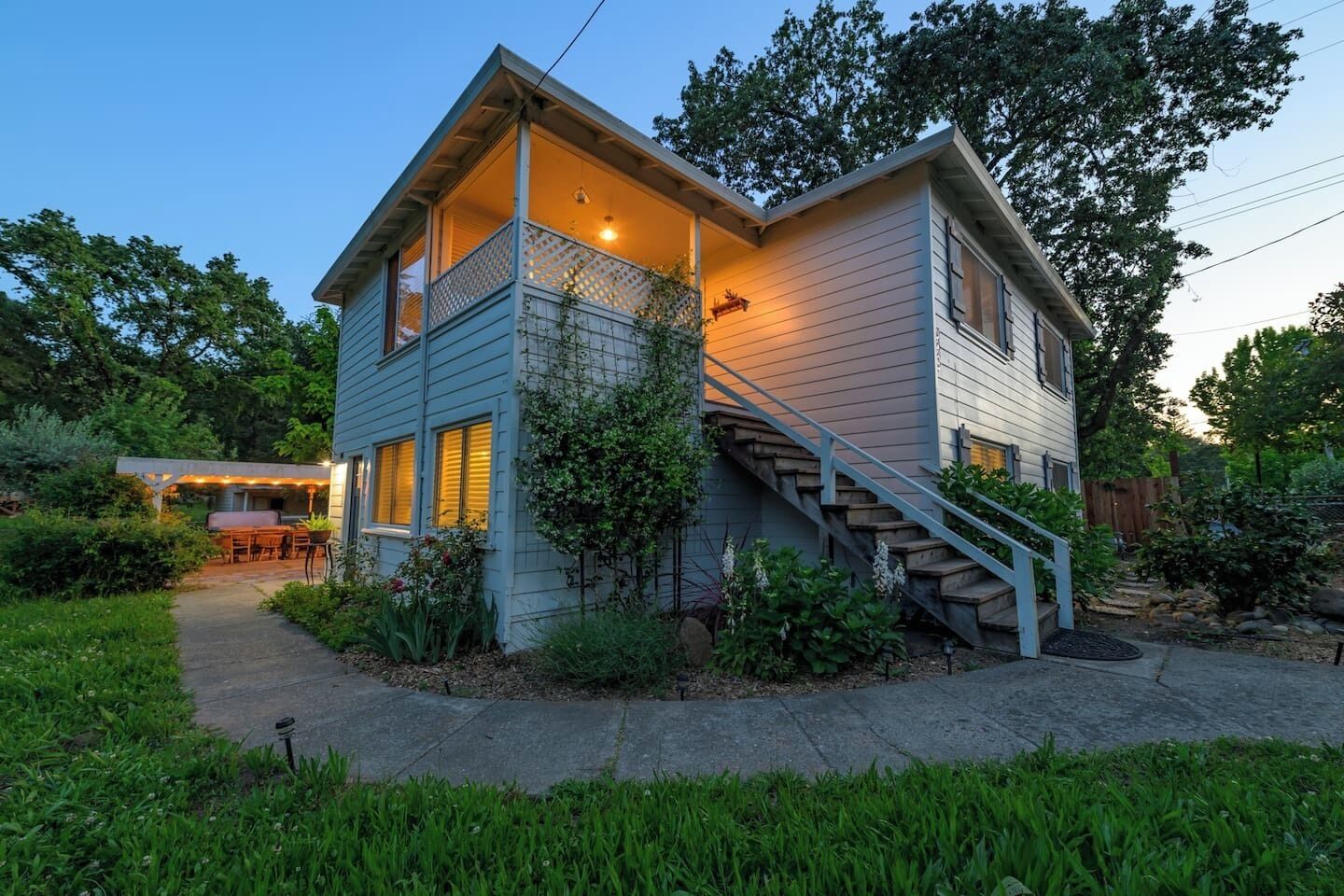 A two-story house with a covered porch, a staircase, and a garden.