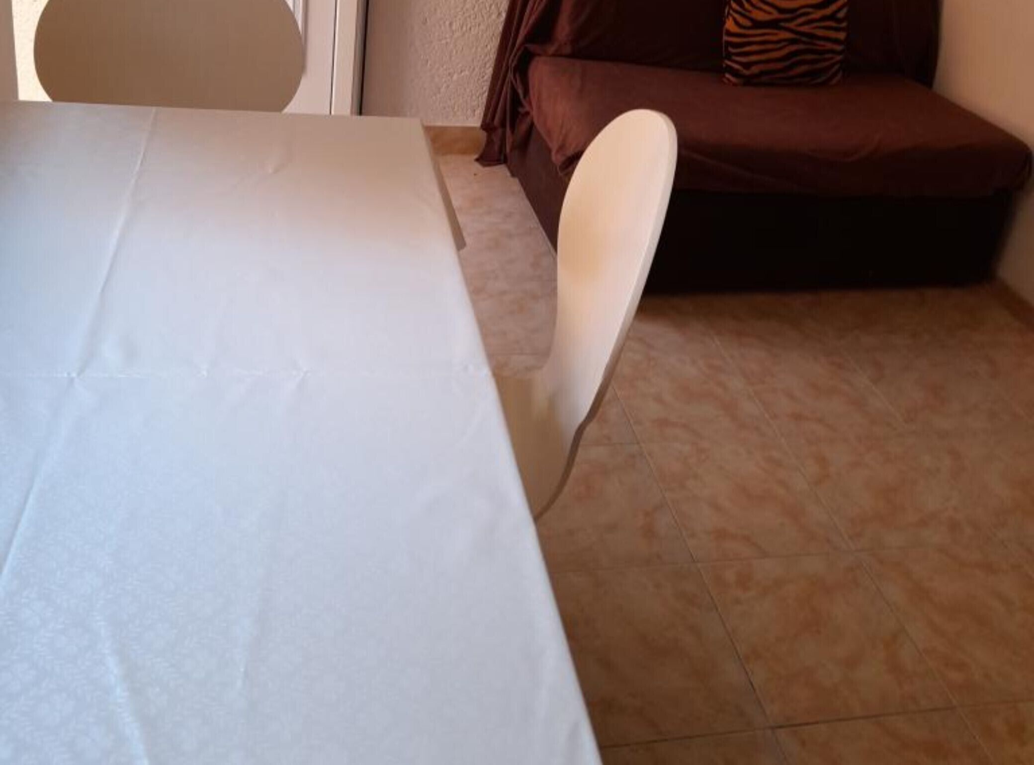 Une pièce avec une table blanche, un canapé marron et une chaise.
