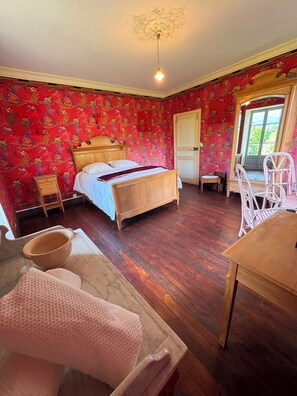 A bedroom with a wooden bed, a small bedside table, a chair, and a table.