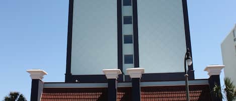 Un bâtiment doté d’une grande tour centrale, d’un toit recouvert de tuiles rouges et d’une façade blanche.