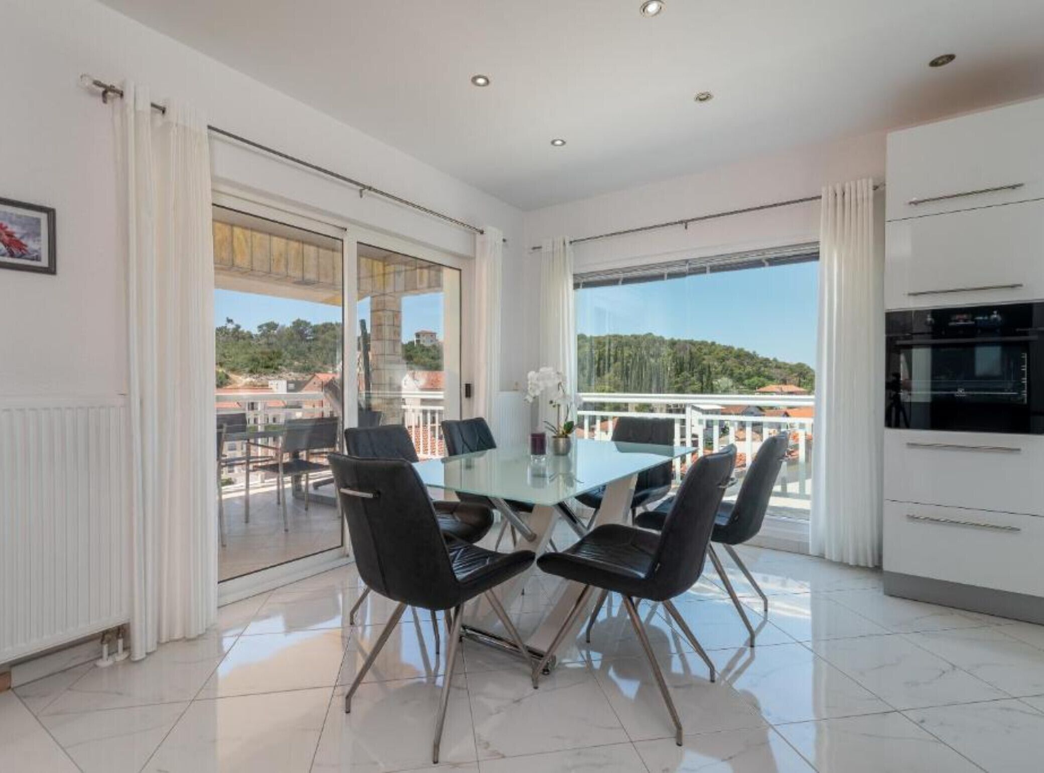 Une cuisine moderne avec un coin repas vitré, une vue sur la ville et un balcon.