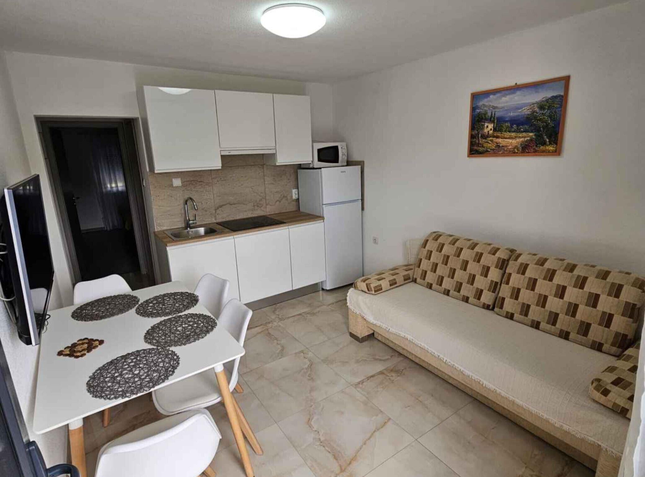Un espacio habitable compacto con kitchenette, comedor con mesa y sillas, y un sofá.