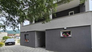 Ein modernes, zweistöckiges Gebäude mit grauem Mauerwerk, einem kleinen Fenster mit Blumen und einem geparkten Auto auf der Auffahrt.