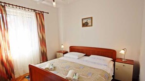 Ein Hotelzimmer mit einem hölzernen Bett, zwei Nachttischen mit Lampen, einem Deckenventilator und einem Fenster mit Vorhängen.