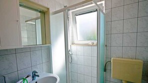 Ein Badezimmer mit Waschbecken, Spiegel, Dusche und Toilette.