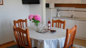 Ein Esstisch mit Stühlen, einer Blumenvase, einer Flasche und einer Fruchtschale.