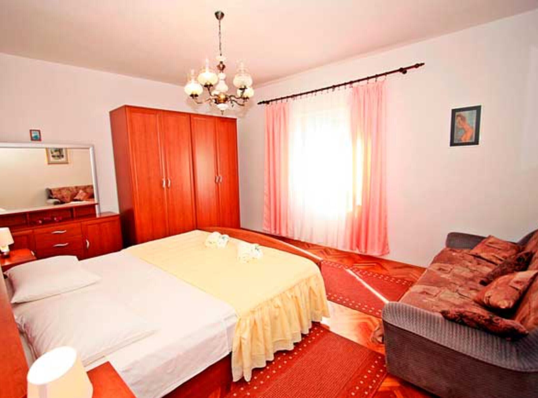 Ein Schlafzimmer mit Bett, Kleiderschrank, Stuhl, Schreibtisch und einer Chandelier.