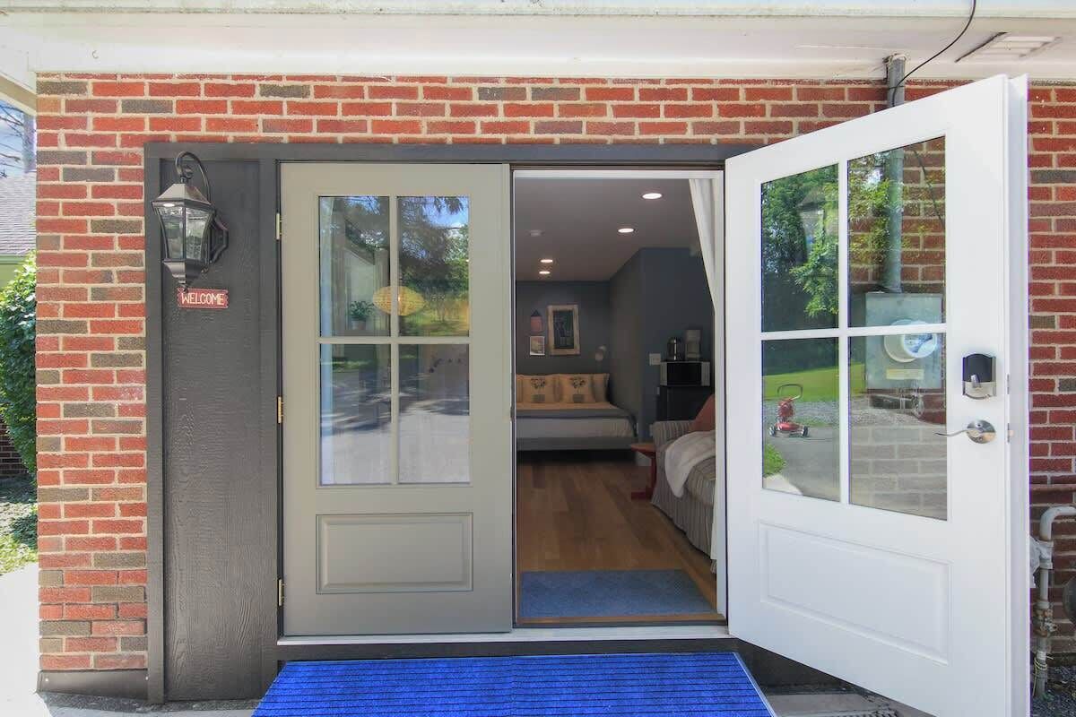 A brick exterior with a sliding glass door leading to a bedroom with a bed and a nightstand.