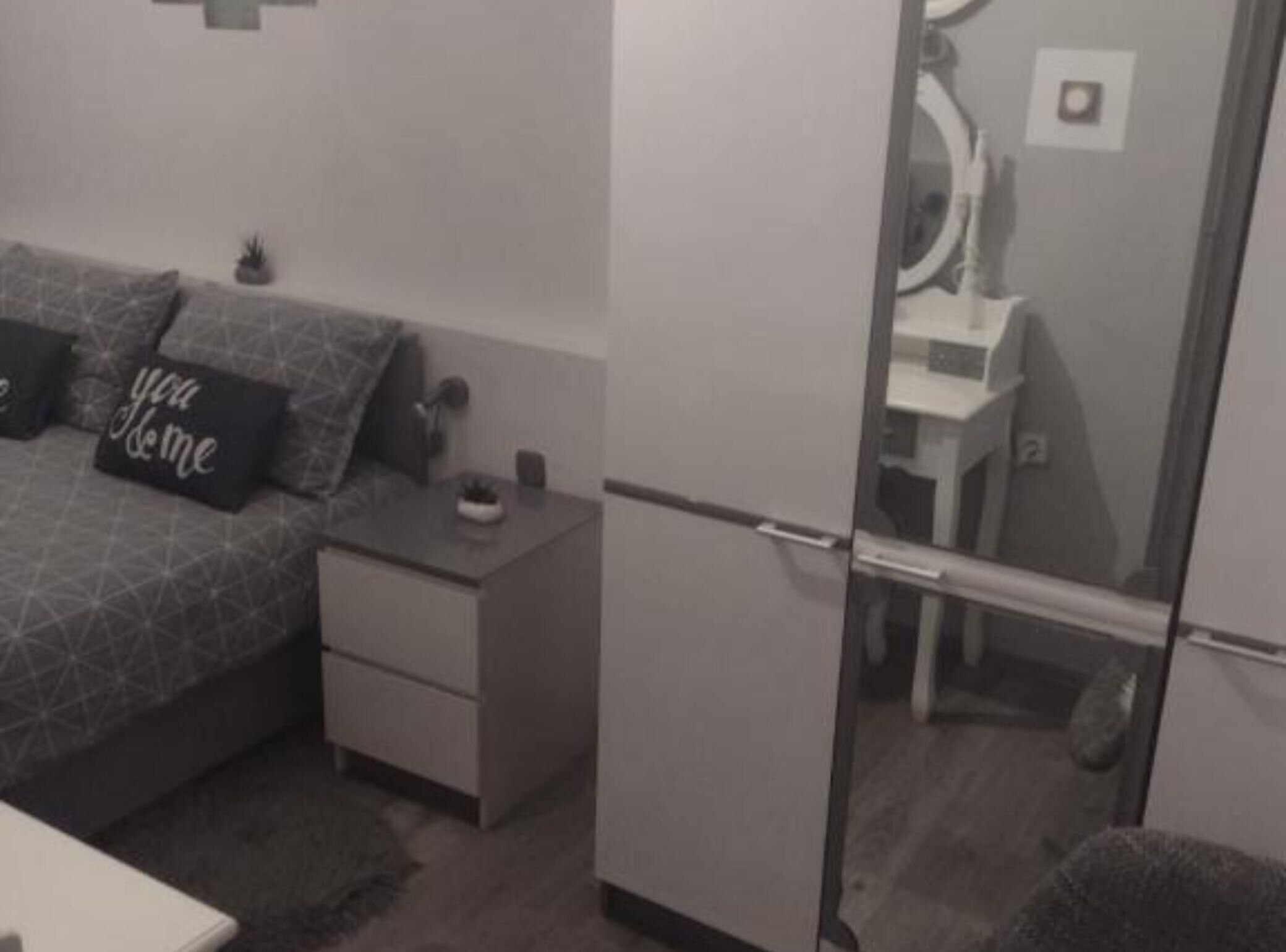 Ein Schlafzimmer mit einem Bett, einem Nachttisch und einem Spiegel.