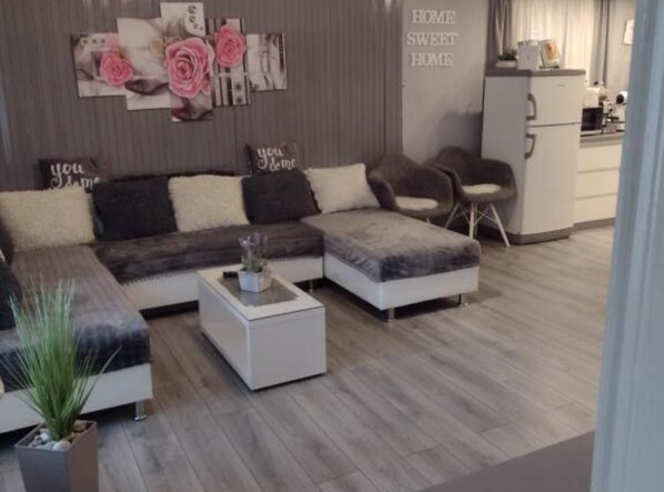 Ein modernes Wohnzimmer mit einer Eckcouch, einem kleinen weißen Couchtisch und einer Wand mit floralen Bildern.