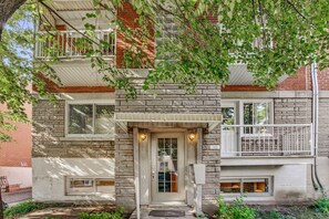 A multi-story building with a stone facade, a central entrance with a door and windows, and a balcony with railings. - Beautiful apartment. Very safe neighborhood. Close to public transportation and amenities. (Montréal)