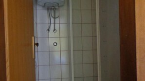 Ein Badezimmer mit Toilette, Duschkabine und gefliesten Wänden.