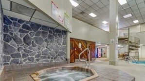 Un espace de bien-être doté d’un mur en pierre, d’un jacuzzi et d’un escalier en colimaçon.