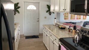Una cocina con armarios blancos, un refrigerador negro, una estufa y un microondas.