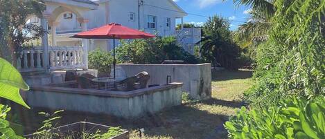 Un quartier résidentiel comprenant une maison, un espace extérieur aménagé pour s’asseoir et un jardin.