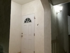 A white door with a small window, a number '4' on the wall, and a wall-mounted light fixture.