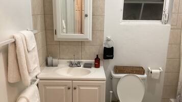 Une salle de bain avec un lavabo blanc, un miroir, des toilettes et un porte-serviettes.