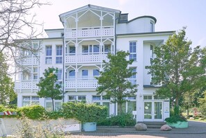 Ein mehrstöckiges Gebäude mit weißer Fassade, Balkonen und einem verschlossenen Eingang.