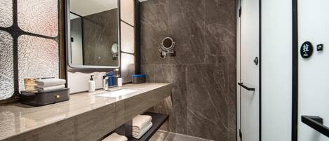 A modern bathroom with a marble vanity, a large mirror, and a shower area.