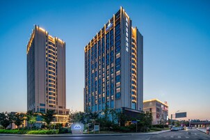 Dois edifícios altos com letreiros iluminados, provavelmente hotéis, e um céu claro ao fundo.