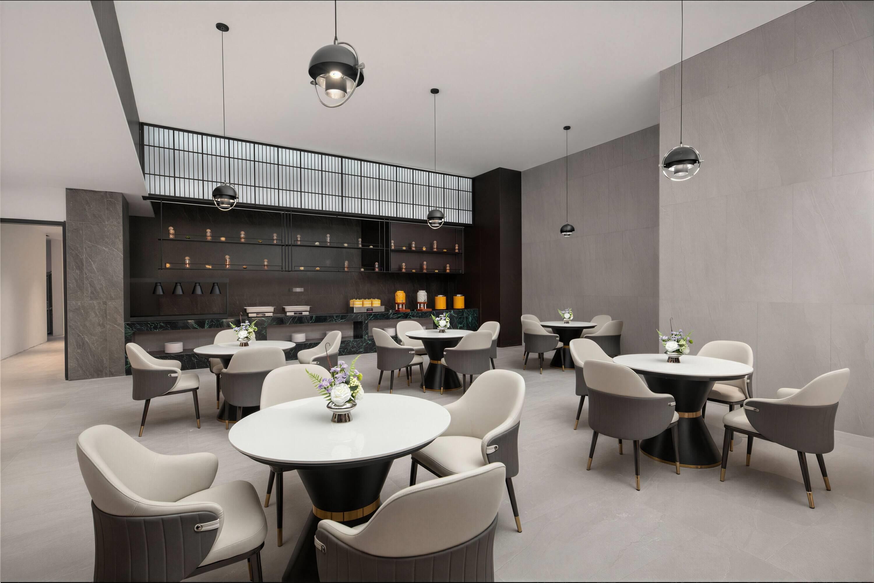 Un espace repas moderne avec des tables et des chaises rondes, une mezzanine dotée d’une rambarde et une étagère murale agrémentée d’objets décoratifs.