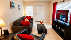 A living room with a sofa, a coffee table, a TV, and a lamp.