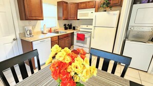A kitchen with wooden cabinets, a white refrigerator, a microwave, a dishwasher, and a table with a bouquet of flowers.