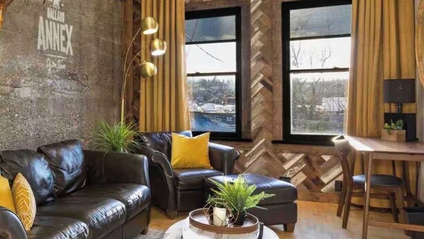 Ein modernes Wohnzimmer mit Wänden im Fischgrätmuster, Ledersofas, einem Marmor-Couchtisch und einem Ausblick durch große Fenster.