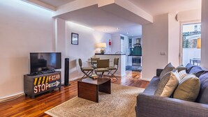 Een moderne woonkamer met een flatscreen televisie, een salontafel en een bank met gestreepte kussens.