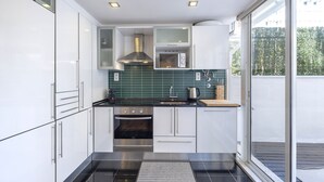 Een moderne keuken met witte kasten, een roestvrijstalen oven, een magnetron en een groene spatwand.
